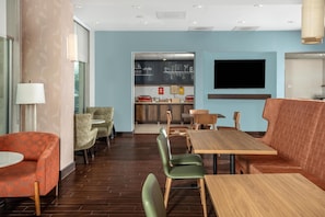 A restaurant with a long wooden table, green chairs, and a red upholstered booth.