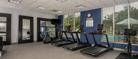 A fitness room with treadmills, exercise bikes, and a wall-mounted TV.