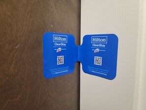 Two blue Hilton CleanStay cards with Lynol protection, attached to a wooden door. - Hampton Inn Austin/Oak Hill (Austin)