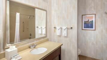 Un baño con un espejo grande, un lavabo, un perchero para toallas y un cuadro en la pared.