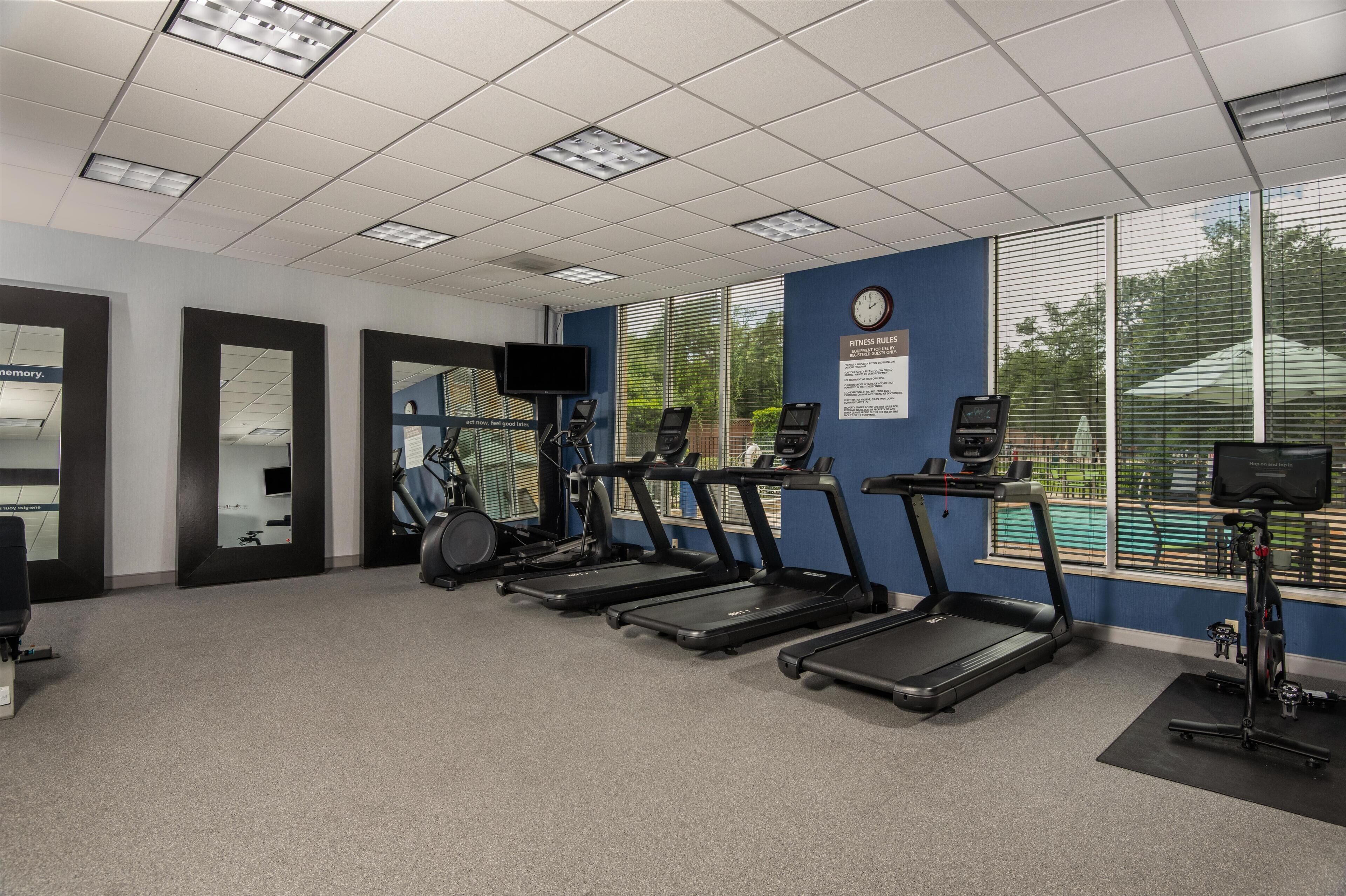 A fitness room with treadmills, exercise bikes, and a wall-mounted TV.