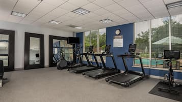 A fitness room with treadmills, exercise bikes, and a wall-mounted TV.