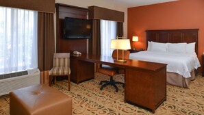Ein Hotelzimmer mit Bett, Schreibtisch, Stuhl, Fernseher und Telefon.