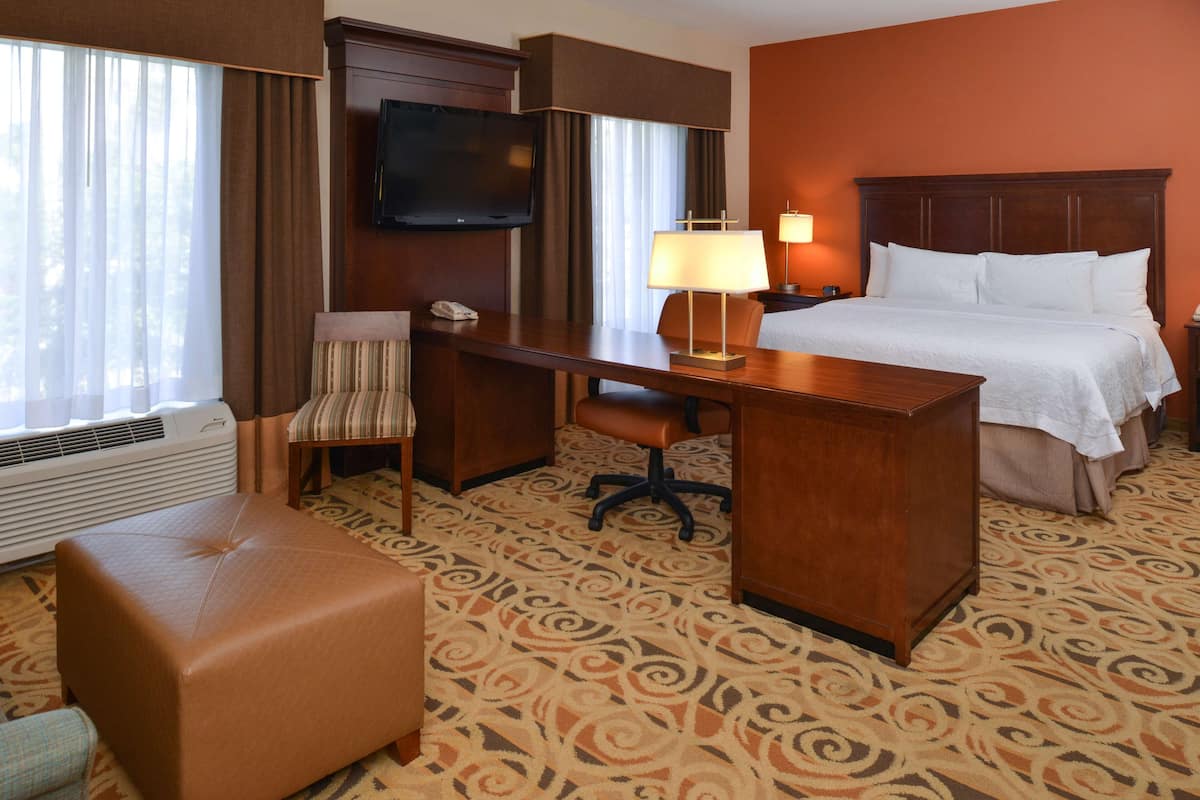 A hotel room with a bed, a desk, a chair, a television, and a telephone.