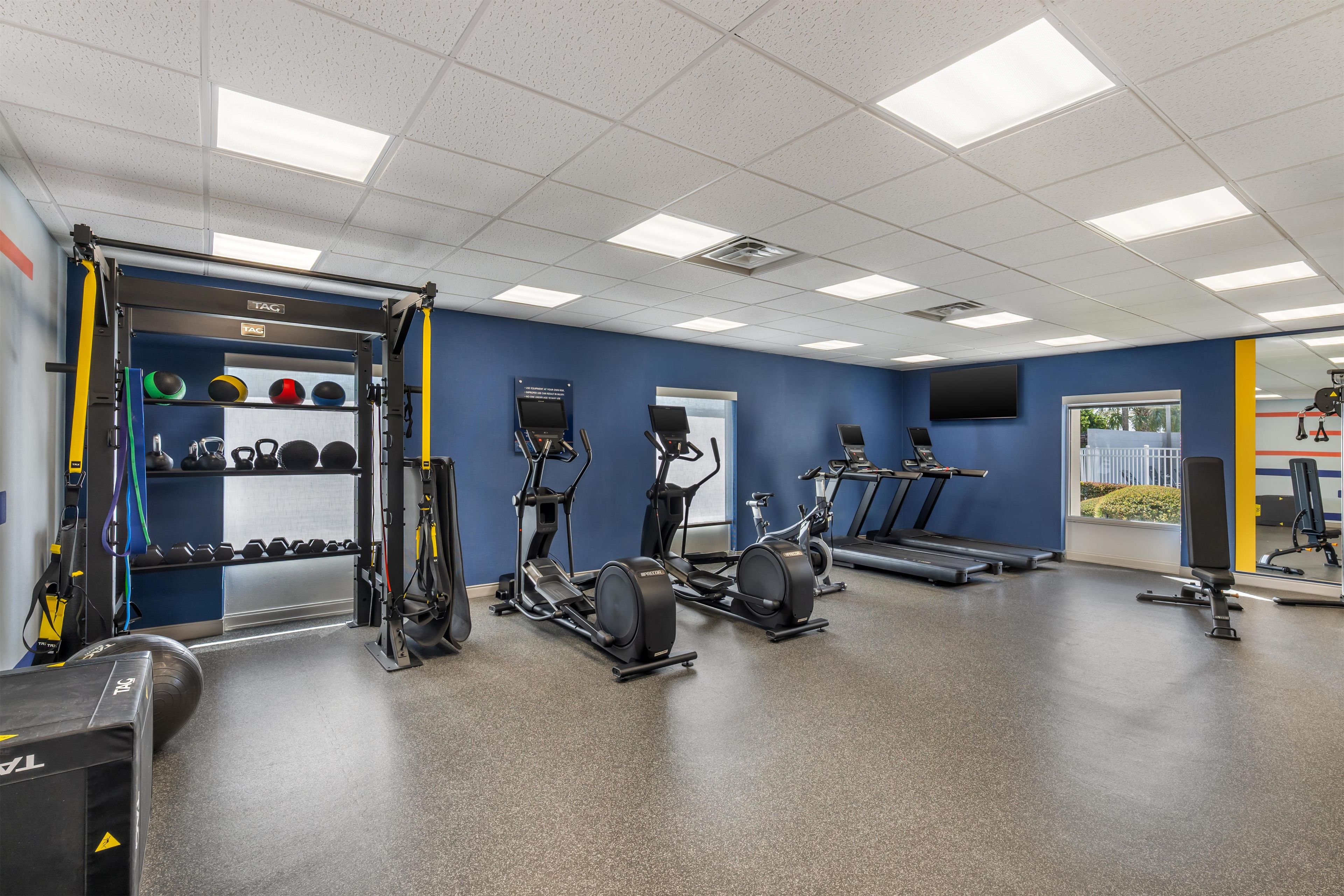 A gym with various exercise equipment, including treadmills, an elliptical, and free weights.