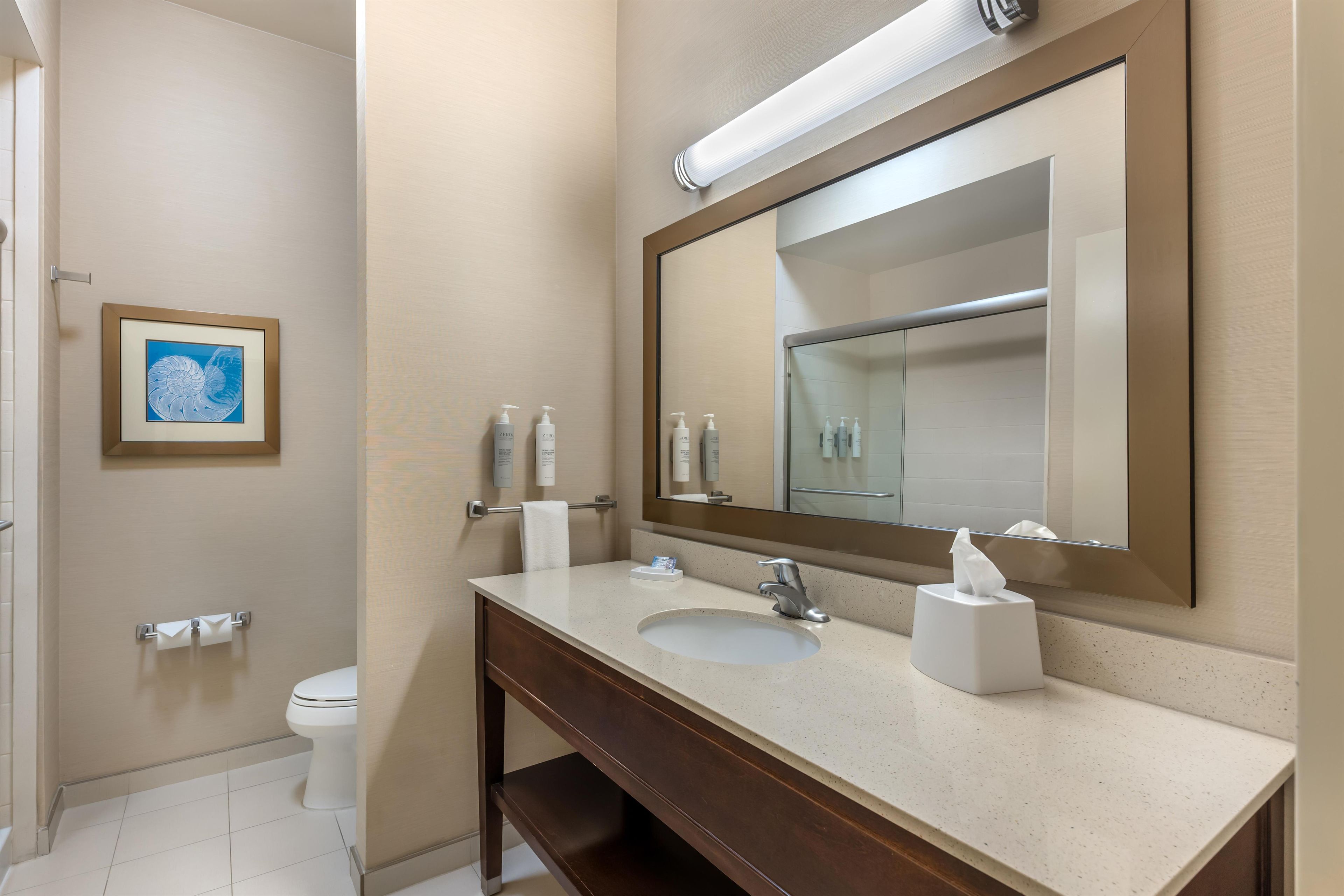 A modern bathroom with a large mirror, a sink, and a toilet.