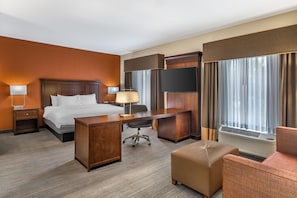 A hotel room with a bed, desk, chair, and large windows. - Hampton Inn & Suites Ocala (Ocala)