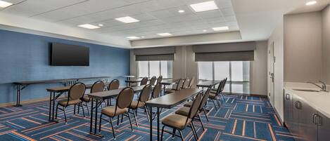 A conference room with a long table, chairs, a flat-screen TV, and a large window.