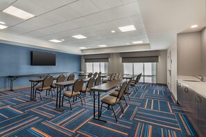Un salón de conferencias con una mesa larga, sillas, un televisor de pantalla plana y un ventanal grande.