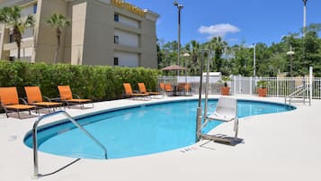 Una piscina con sillas de descanso y un edificio con la leyenda "Best Western" al fondo.