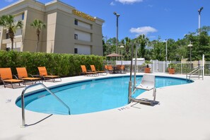 Una piscina con sillas de descanso y un edificio con la leyenda "Best Western" al fondo.