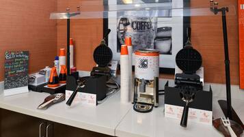 A waffle station with waffle makers, waffle cups, and syrup dispensers.