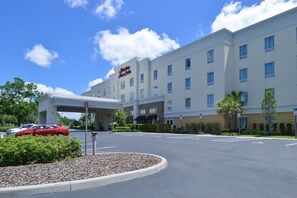 Un hotel de diseño moderno, con un amplio dosel en la entrada y numerosas ventanas.