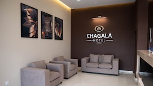 A modern hotel lobby with three sofas, a reception desk, and wall-mounted artwork. - Chagala Aksai (Aksay)