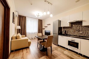 A modern kitchen with a dining area, a sofa, and a television. - Chagala Aksai (Aksay)