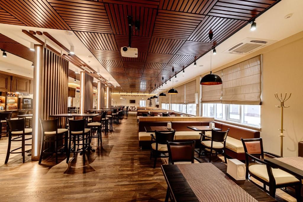 A spacious restaurant with high ceilings, wooden paneling, and large windows.