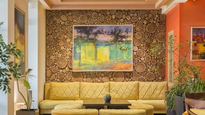 A yellow sofa with a cushion, a small table, and a painting on the wall. - Hotel Lirak (Tetovo)