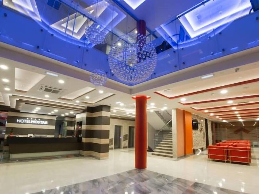 A hotel lobby with a reception desk, seating area, and a staircase.