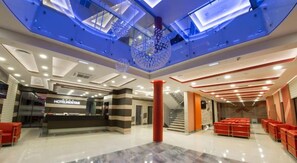 A hotel lobby with a reception desk, seating area, and a staircase. - Hotel Mostar (Mostar)