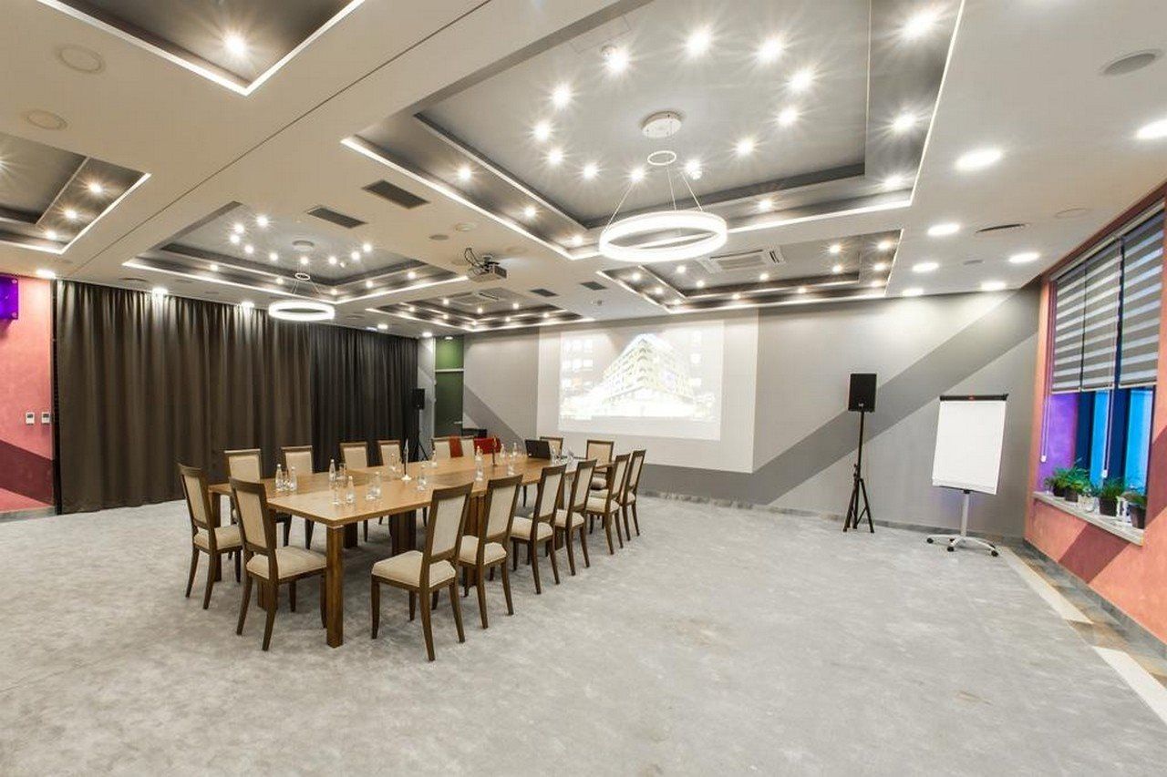 A conference room with a long table, chairs, a projector screen, and a whiteboard.