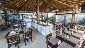Un restaurant spacieux avec des poutres en bois au plafond, de grandes fenêtres et un îlot central doté de sièges.