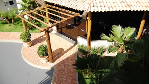 Un espace extérieur abrité, doté d’un toit en tuiles, d’une pergola en bois et de plantes en pot.