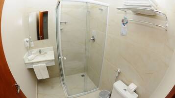Un baño moderno con cabina de ducha de vidrio, lavamanos con espejo e inodoro.