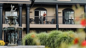 Un edificio con una fuente, asientos al aire libre y un balcón con una persona.
