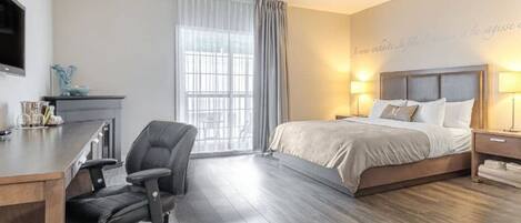A hotel room with a bed, desk, chair, and a TV on the wall.