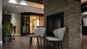 Un vestíbulo con una pared de acento de piedra, una chimenea y dos sillones alrededor de una pequeña mesa.