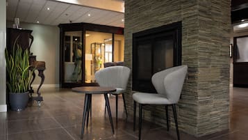 A lobby with a stone accent wall, a fireplace, and two chairs around a small table.