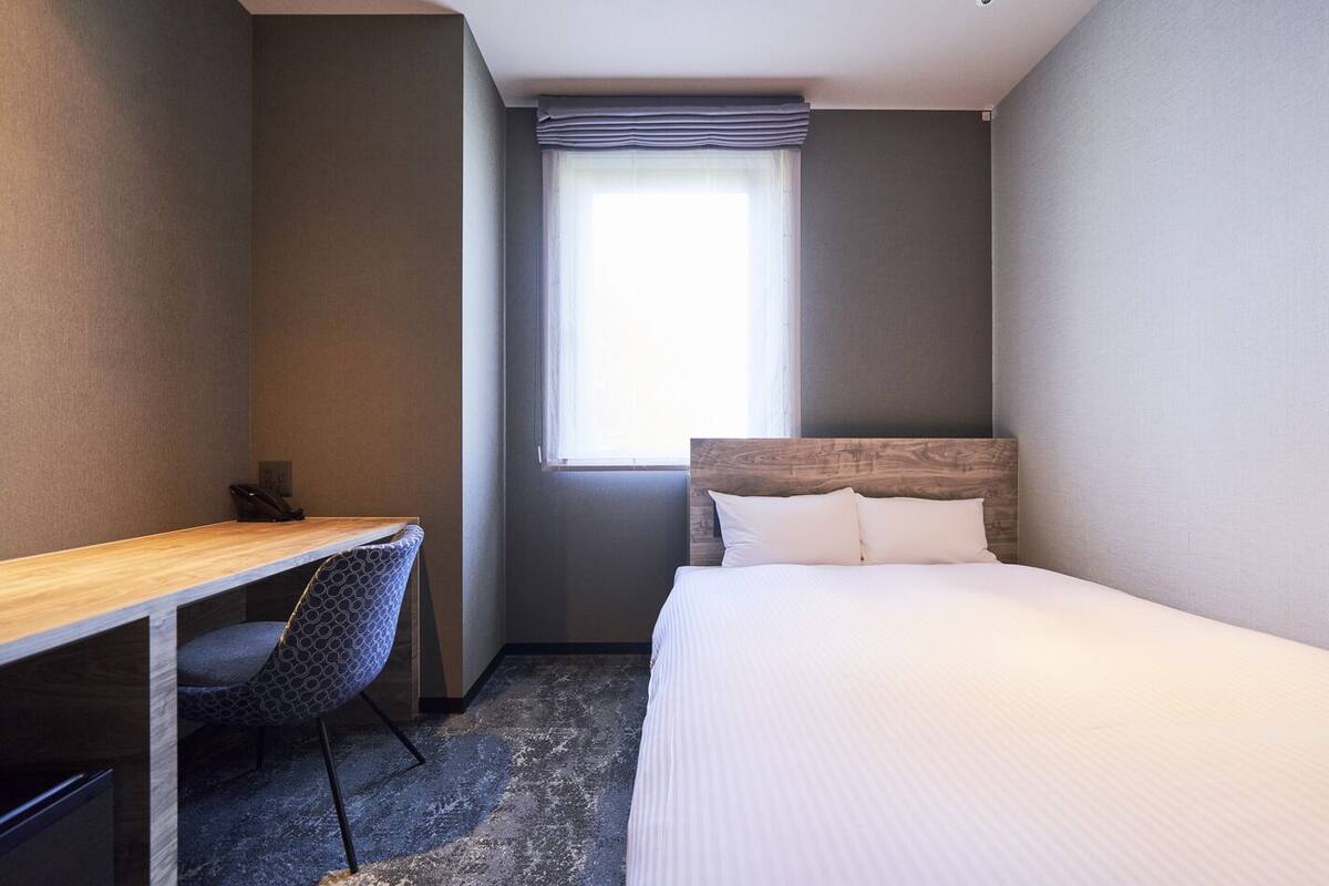 Ein Hotelzimmer mit Bett, Schreibtisch und Stuhl.