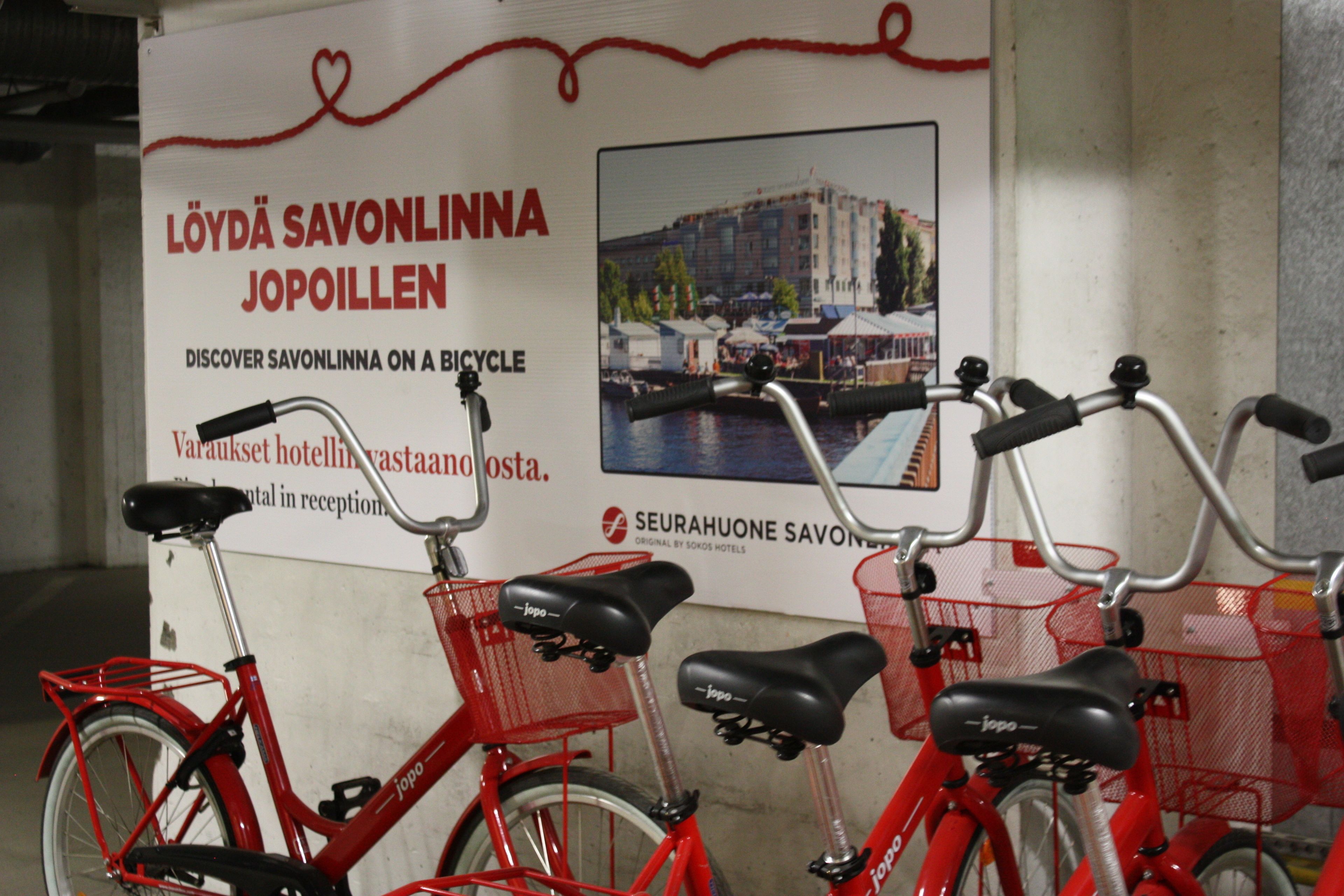 A bicycle rental station with red bicycles and baskets.