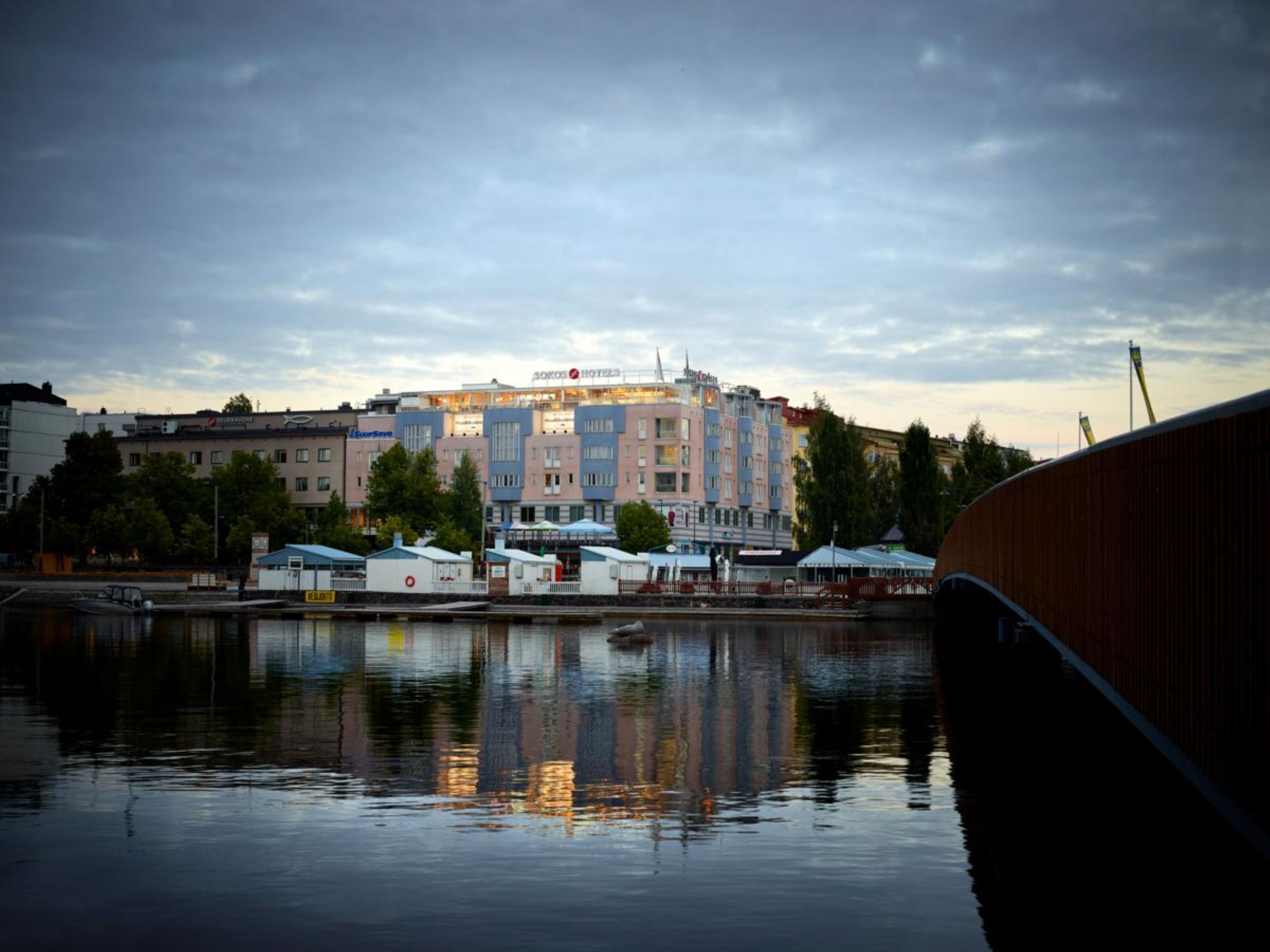 A waterfront hotel with multiple buildings, a dock, and a reflection in the water.