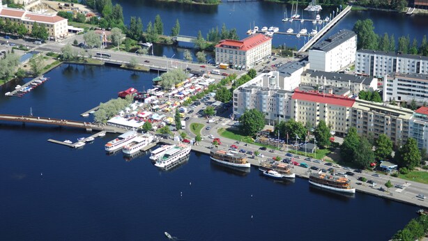 Vue aérienne d’une zone riveraine comprenant un port de plaisance, plusieurs bâtiments et un pont.