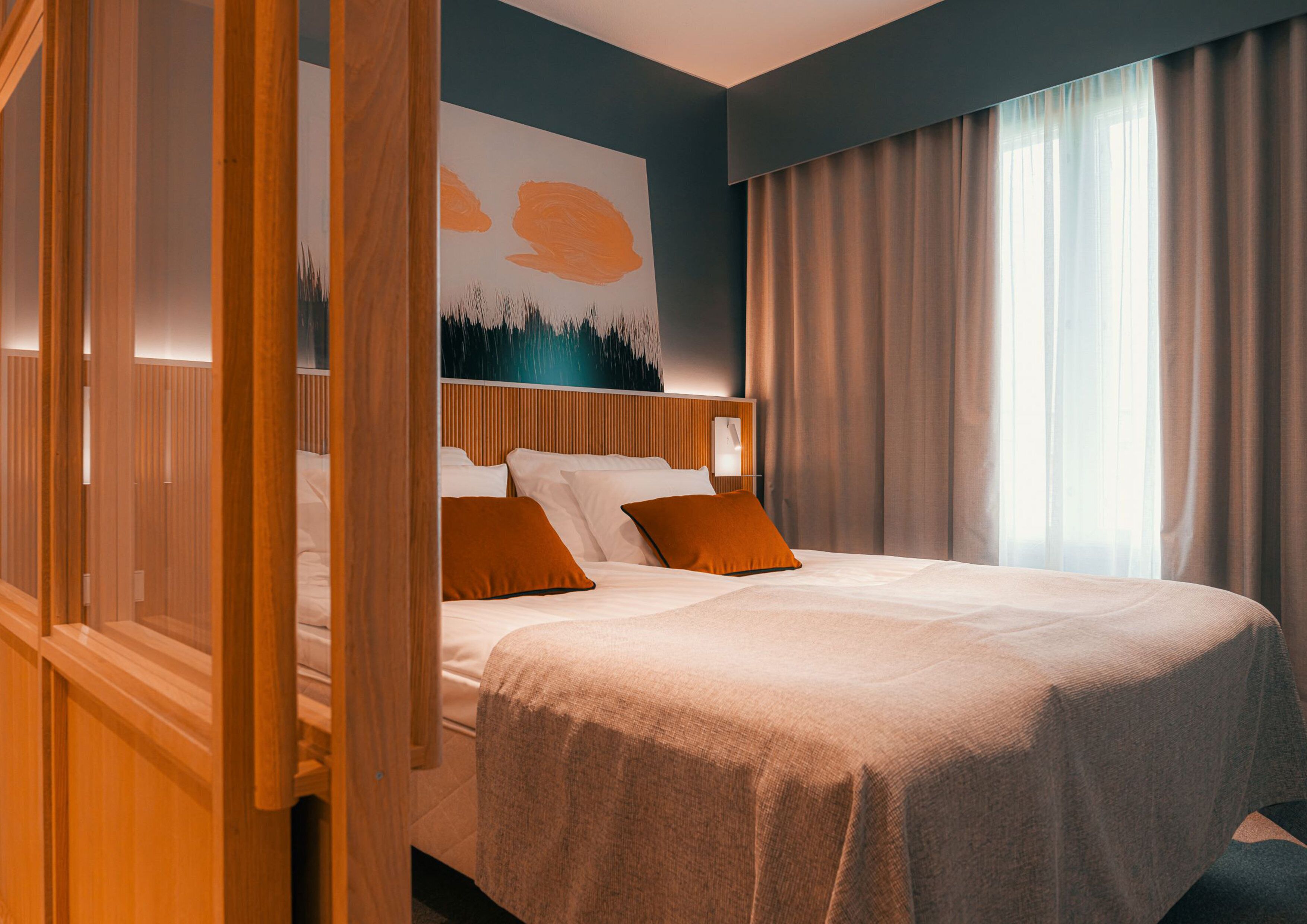 A hotel room with a large bed, wooden headboard, and a painting on the wall.