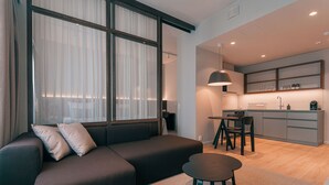 Un salon moderne comprenant un canapé, une petite table et un coin cuisine avec une table à manger et des chaises.