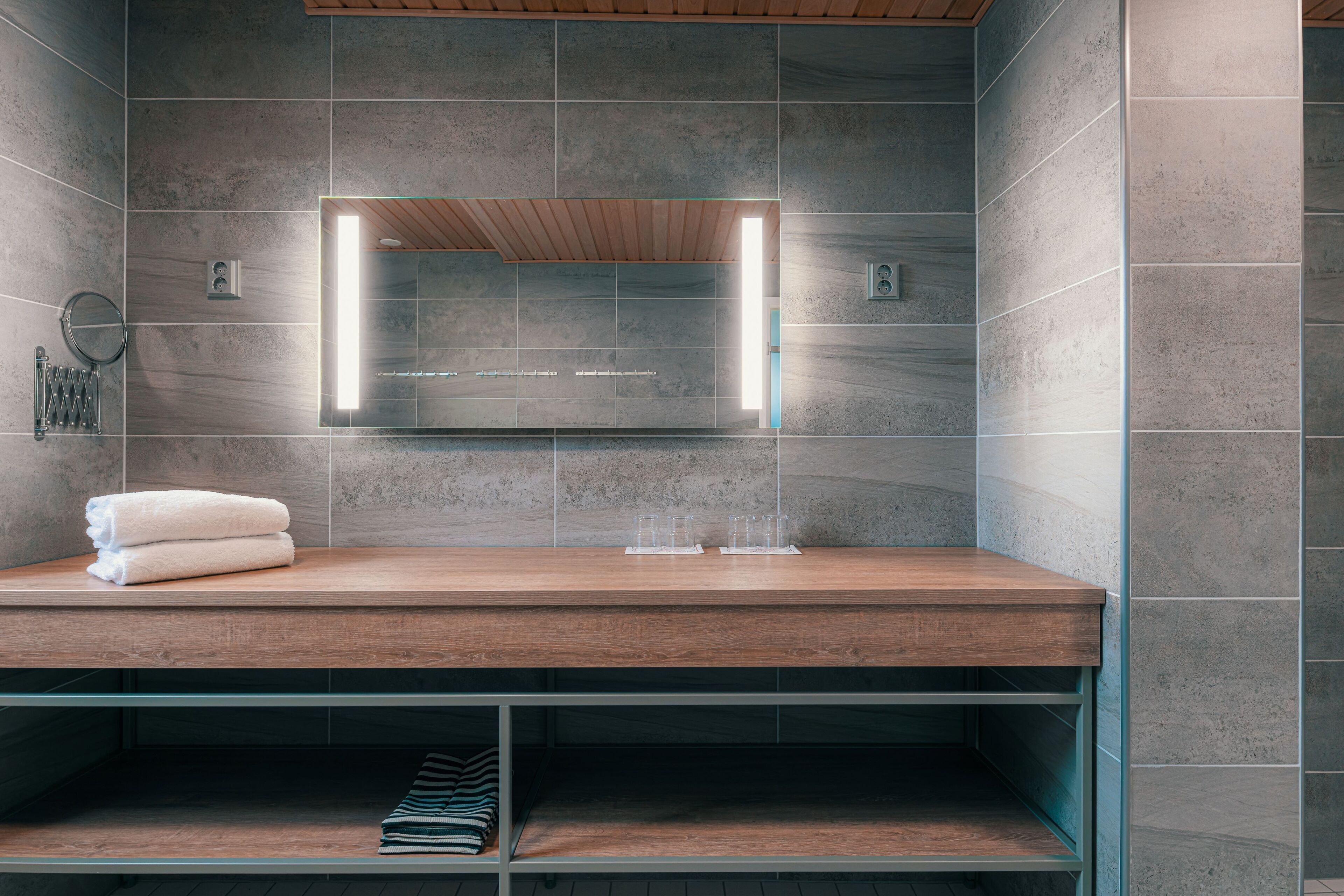 A modern bathroom with a wooden vanity, a mirror, and a towel.