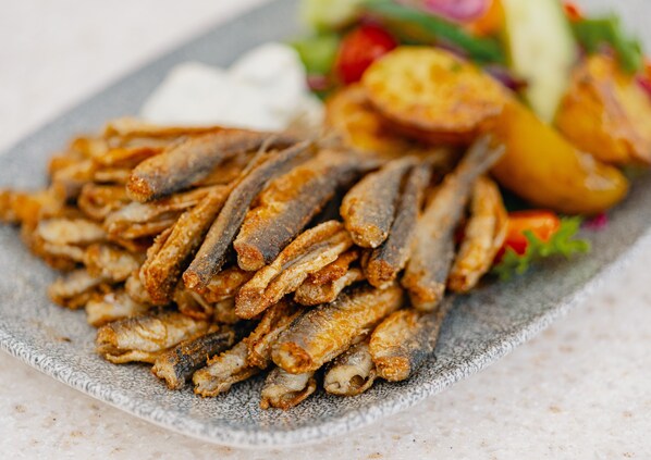 A plate of fried fish with a side salad and roasted potatoes.
