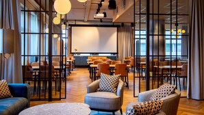 Une salle de conférence spacieuse, dotée d’un grand écran, de plusieurs tables et de chaises disposées pour les réunions.