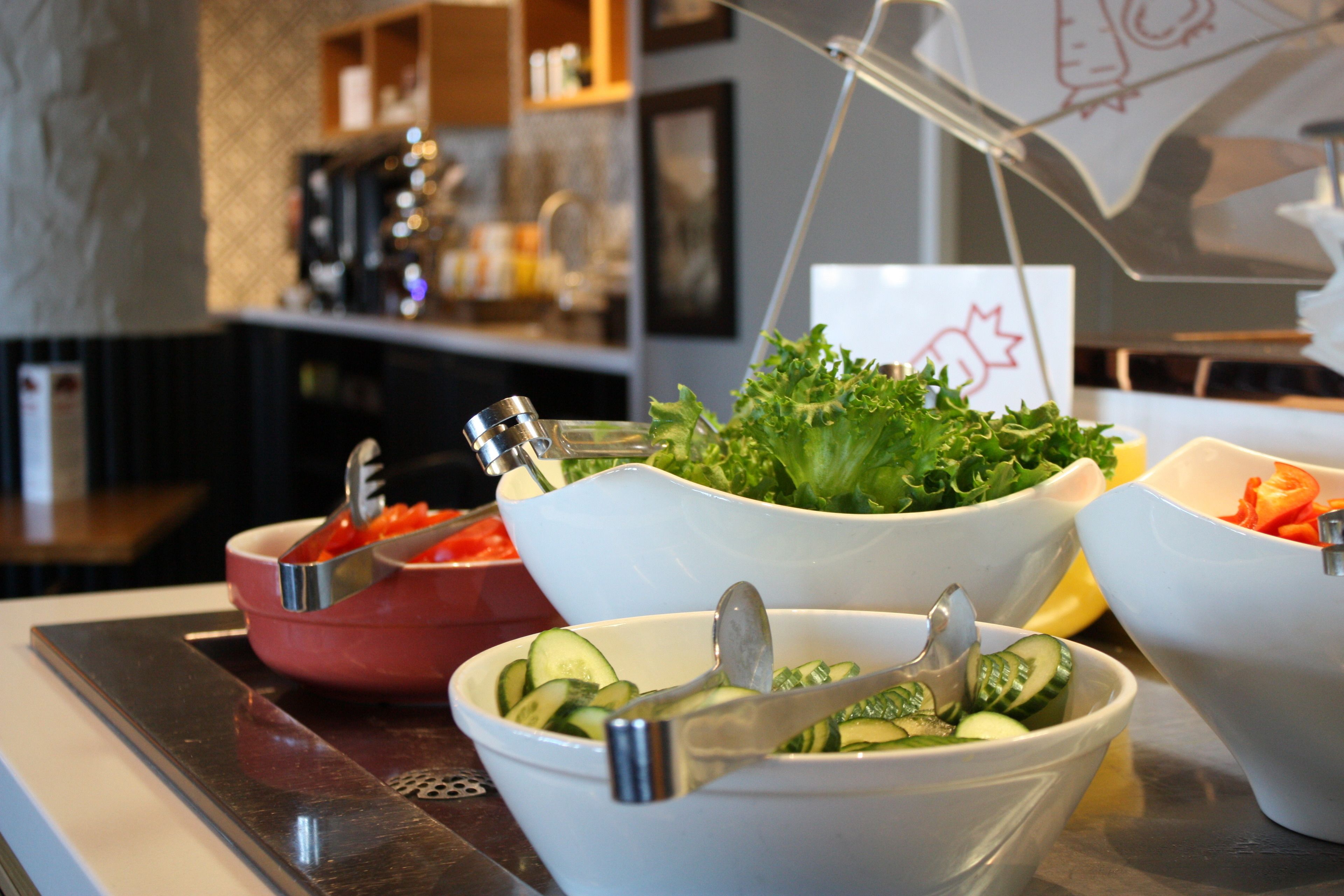 A buffet with various bowls of food, including salads and vegetables.