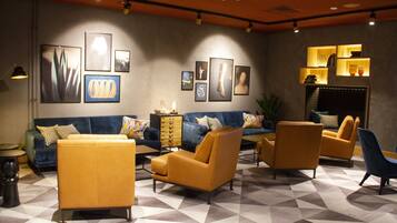A modern living room with a blue sofa, yellow armchairs, and a patterned floor.