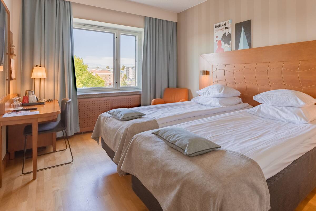 Une chambre d’hôtel avec deux lits, un bureau et une chaise.