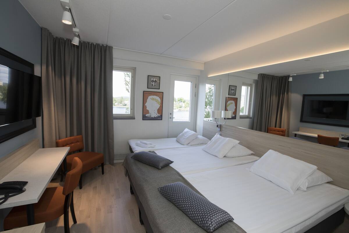 Une chambre d’hôtel avec deux lits, un bureau, une chaise et un téléviseur.