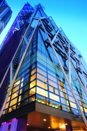 A modern high-rise building with a glass facade and a distinctive triangular architectural feature.