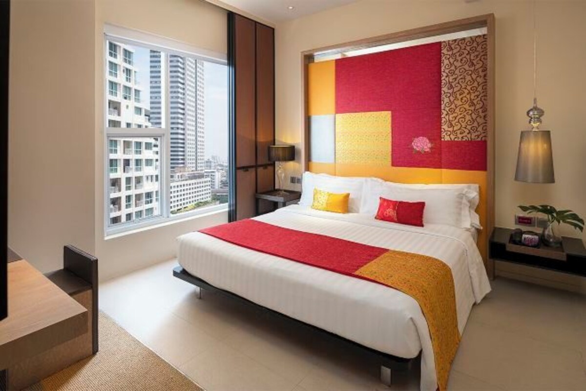 Una habitación de hotel moderna con una cama grande, vistas a la ciudad y un cabecero decorativo.