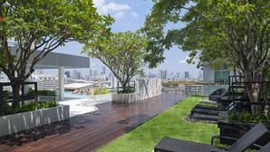 Terraza en la azotea con piso de madera, césped verde y sillas de descanso.