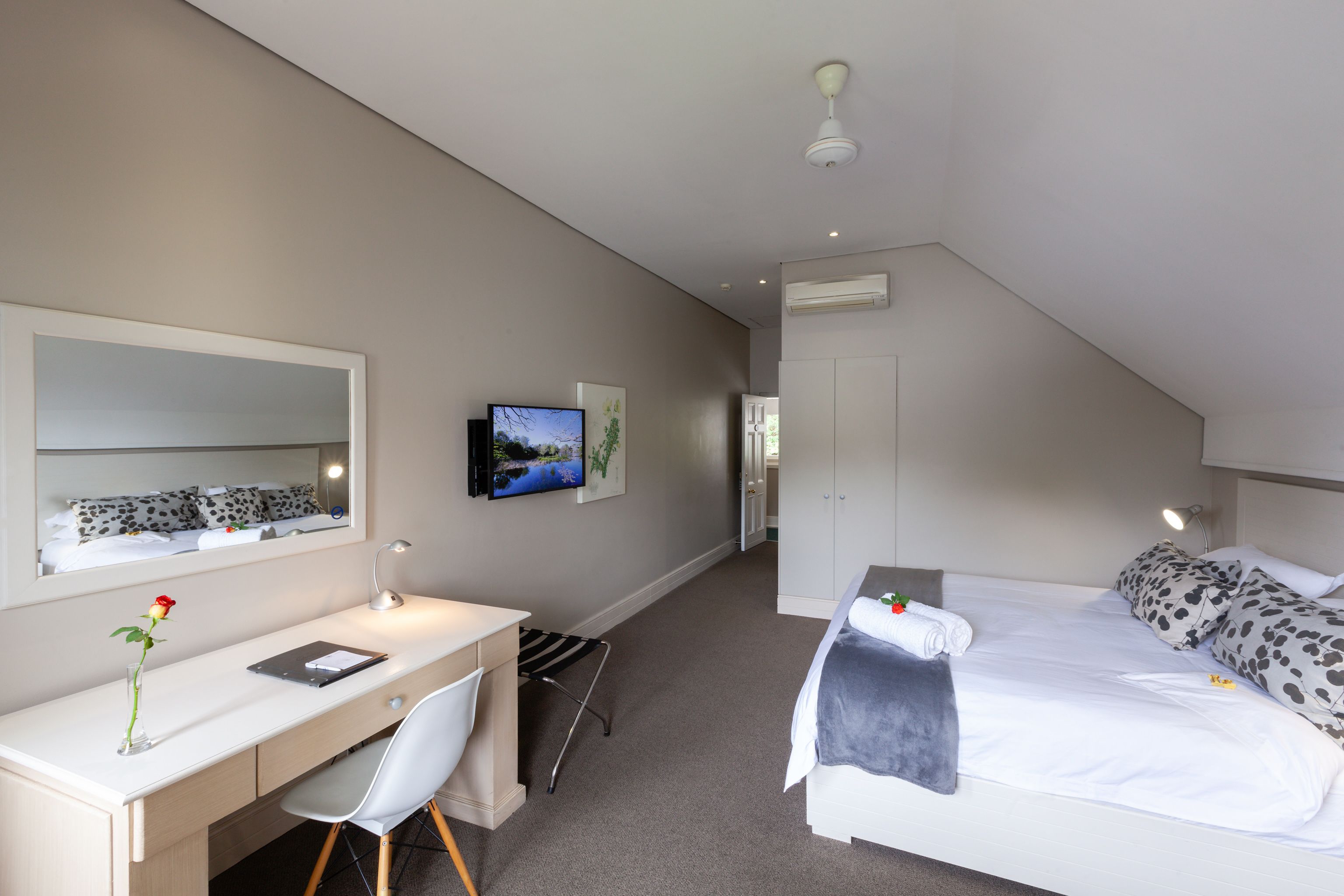 Una habitació d'hotel moderna amb una taula, una cadira i un llit amb un coixí de disseny únic.
