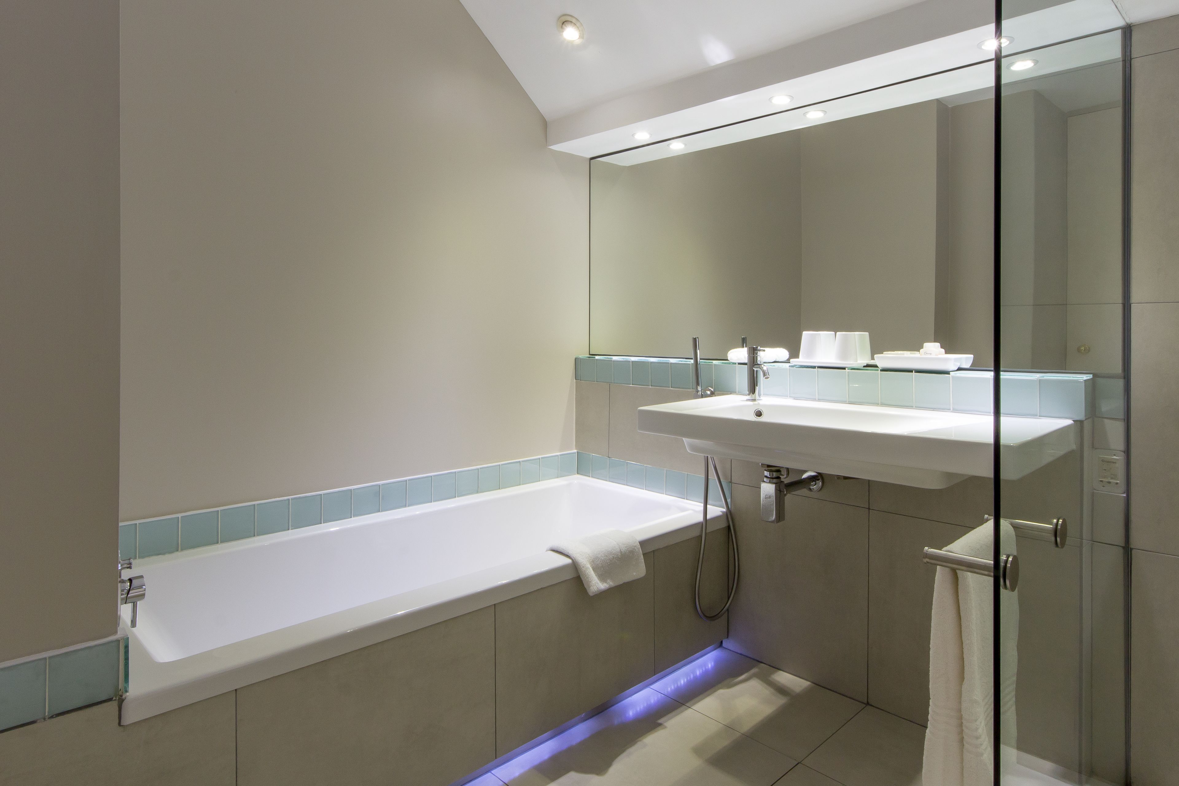 A modern bathroom with a glass-enclosed shower, a bathtub, and a sink.