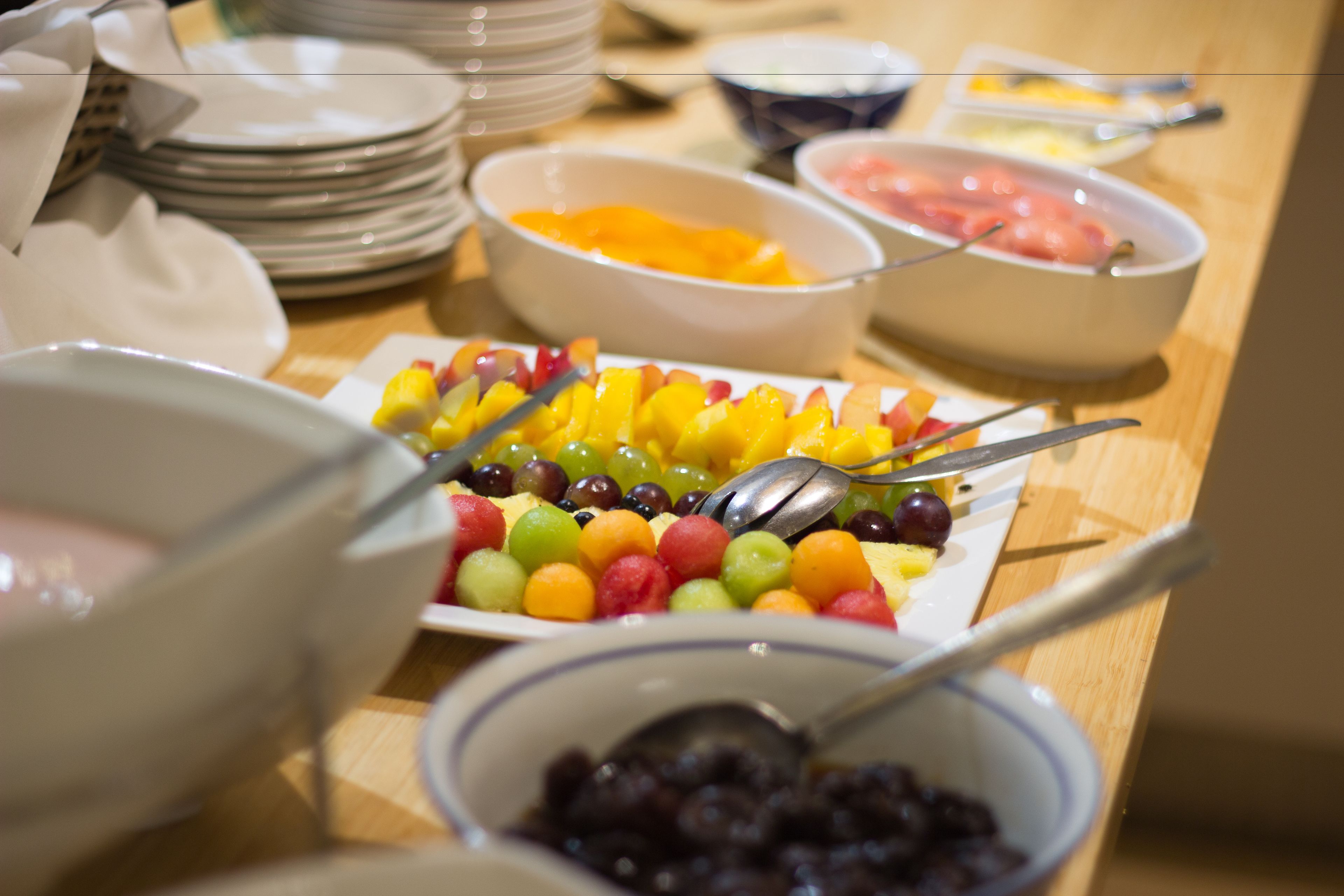 Una mesa de buffet con diversos platos, incluyendo frutas y un tazón de frijoles negros.